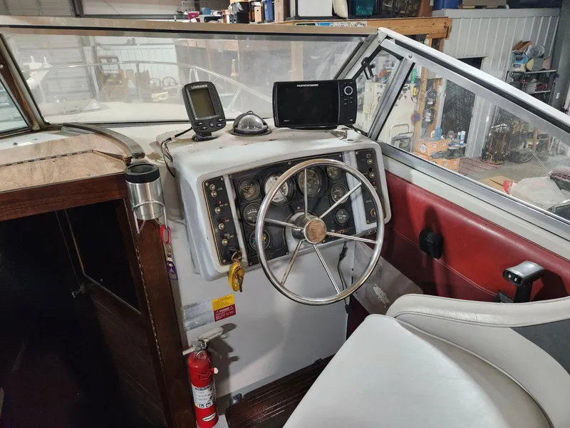 Slide: The Image of 1987 Larson 23 Cuddy Cabin boat dashboard with steering wheel and navigation equipment. - 7