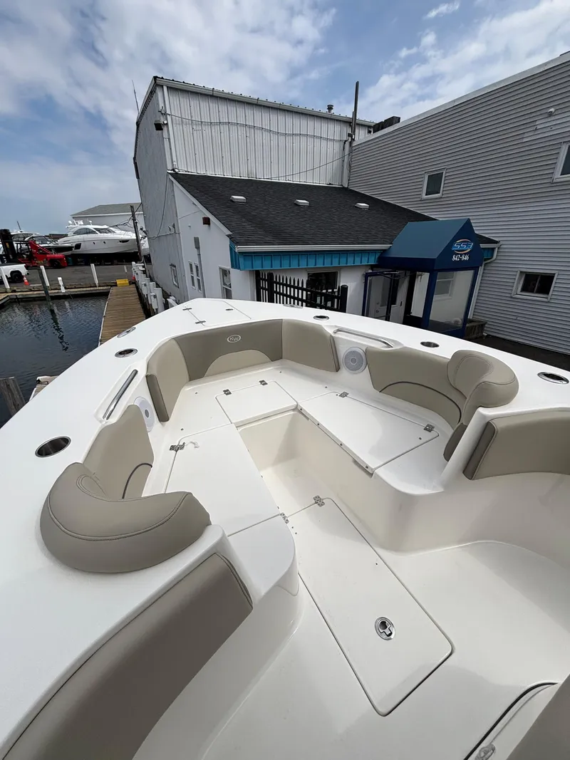 Slide: The Image of 2023 Key West 263FS boat with spacious seating, docked near a marina building. - 11