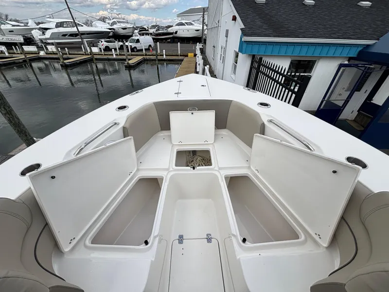Slide: The Image of 2023 Key West 263FS boat with open storage compartments at a marina. - 13