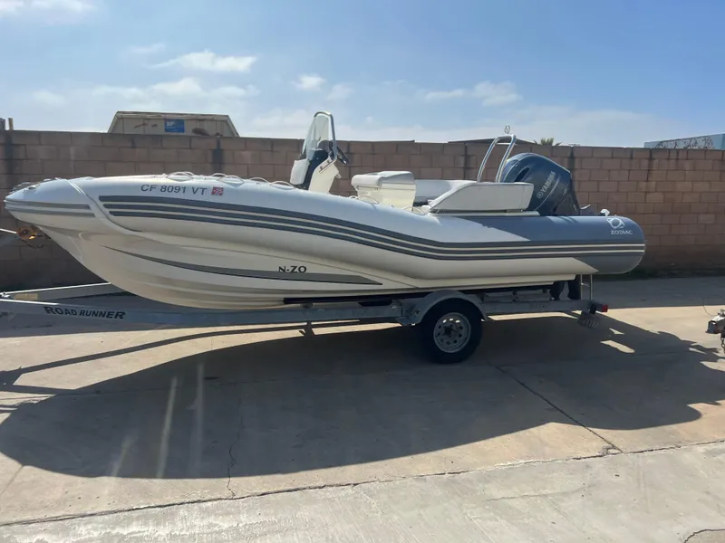 Slide: The Image of 2020 Zodiac N-ZO 600 boat on trailer, parked outdoors under clear sky. - 3