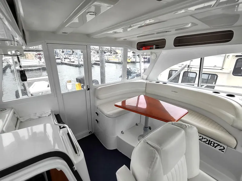 Slide: The Image of 2005 Glacier Bay 3490 Ocean Runner interior with white seating and wooden table, docked at marina. - 45