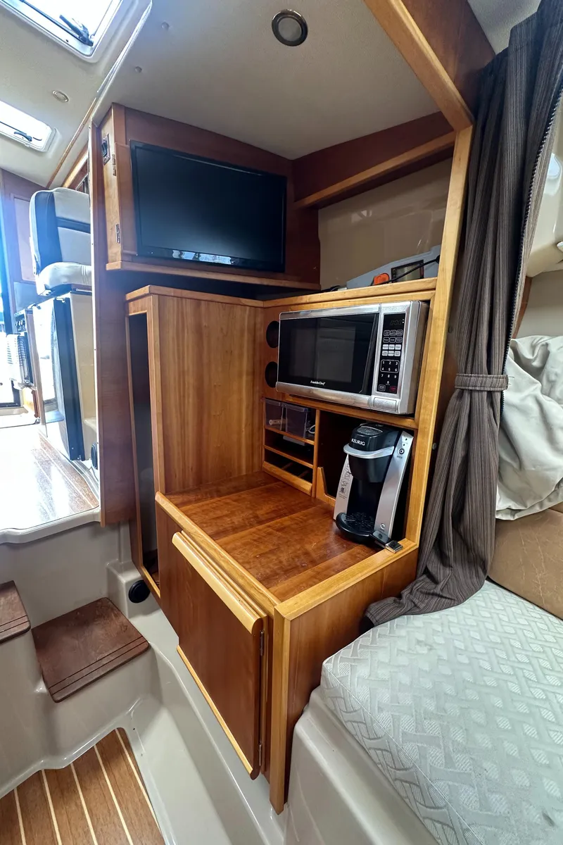 Slide: The Image of 2016 Cutwater 28 interior with TV, microwave, and coffee maker in wooden cabinetry. - 18