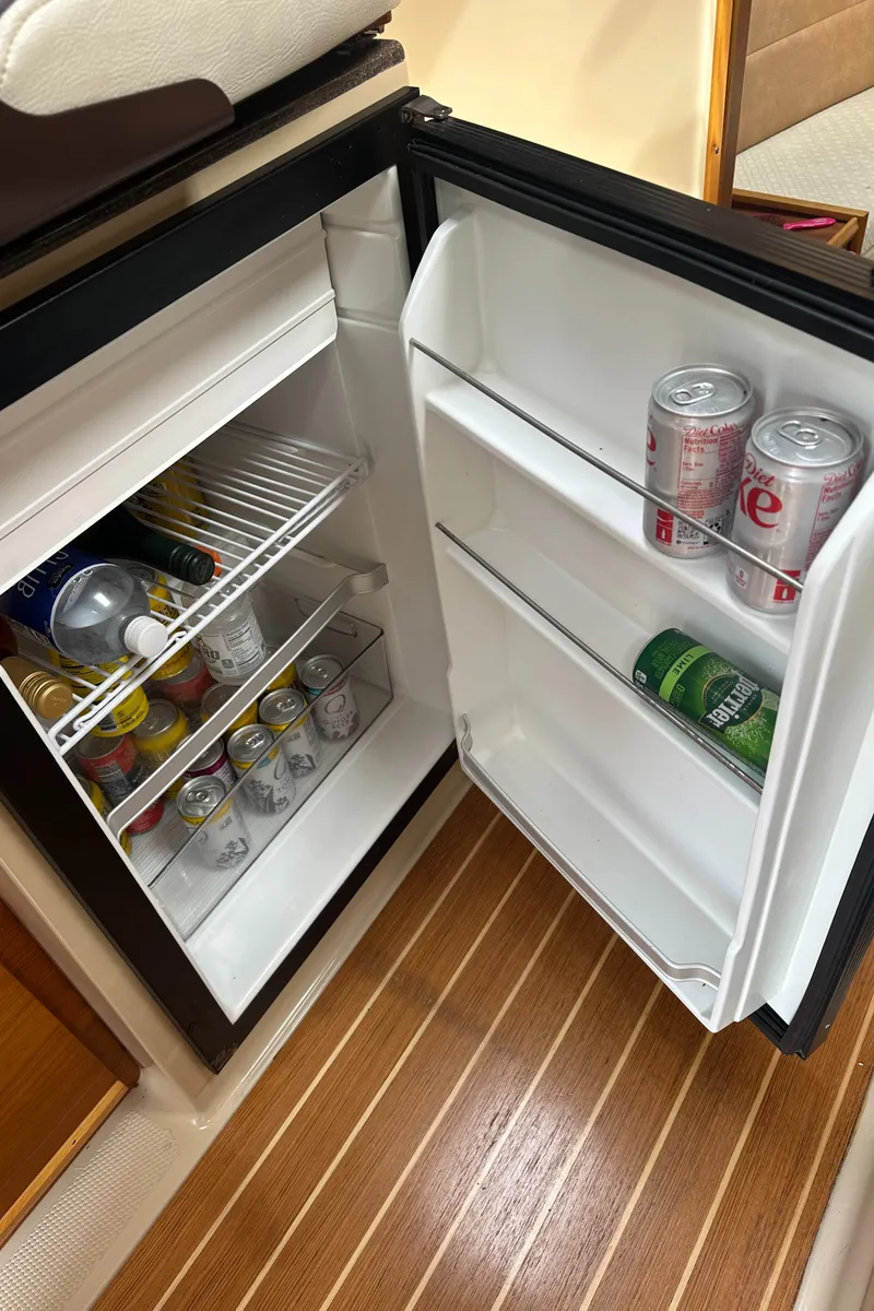 Slide: The Image of Mini fridge stocked with beverages on a 2016 Cutwater 28 boat, featuring wooden flooring. - 20
