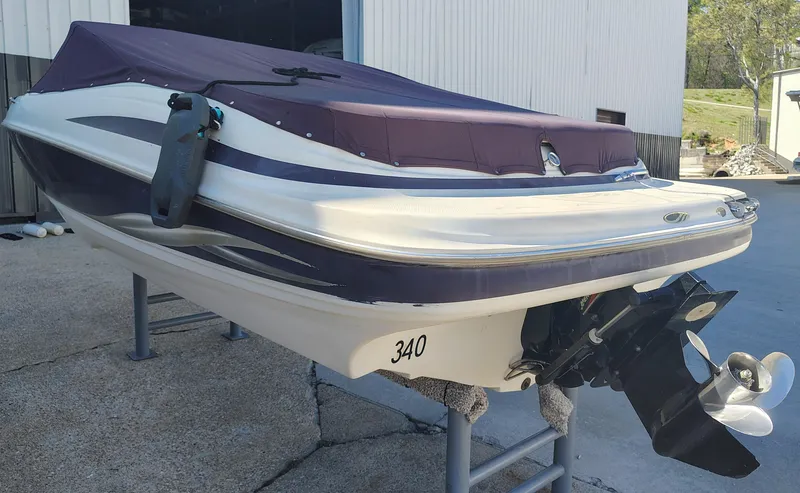 Slide: The Image of 2000 Maxum 1900 SR boat with cover, displayed on a stand outside a building. - 12