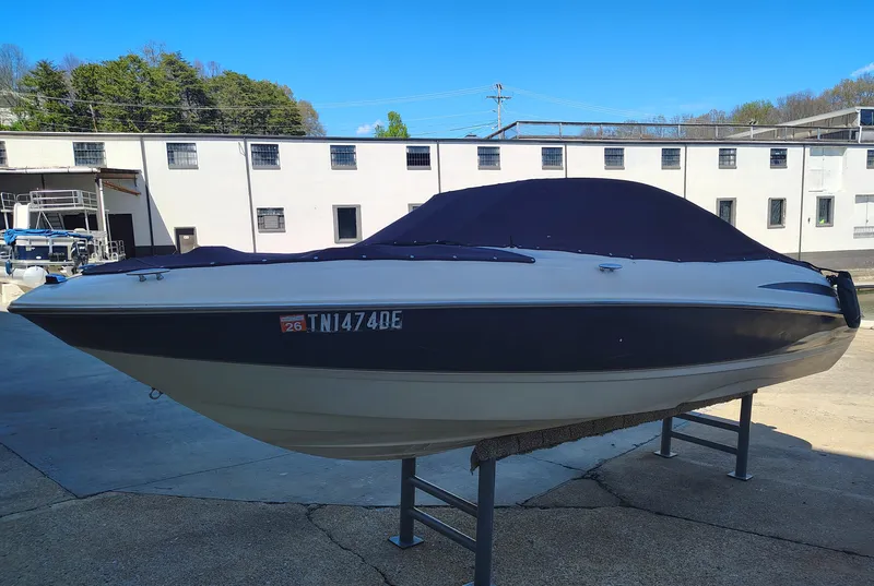 Slide: The Image of 2000 Maxum 1900 SR boat with cover, parked on a stand in a marina. - 13