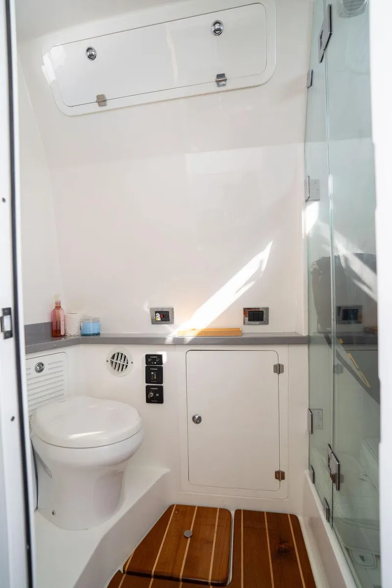 Slide: The Image of 2019 HCB 53 boat bathroom with toilet, shower, and wooden flooring. - 13