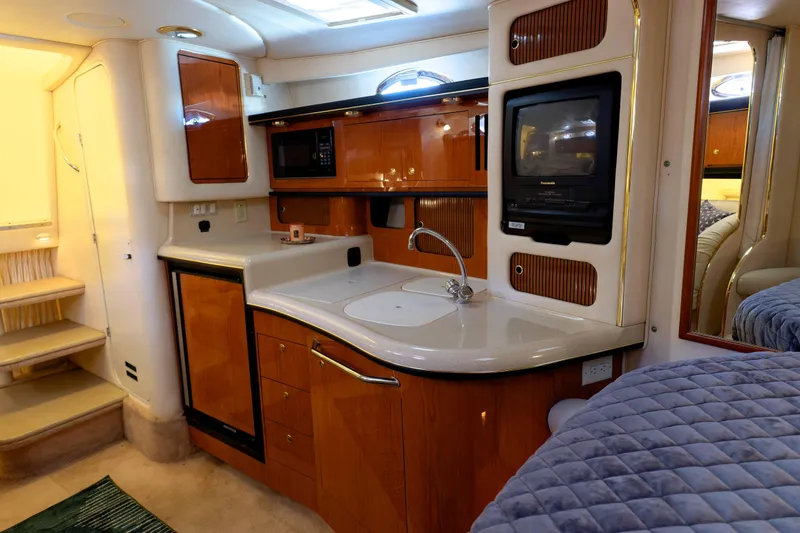 Slide: The Image of Interior of 2000 Sea Ray 340 Sundancer yacht with kitchenette and cozy cabin features. - 16