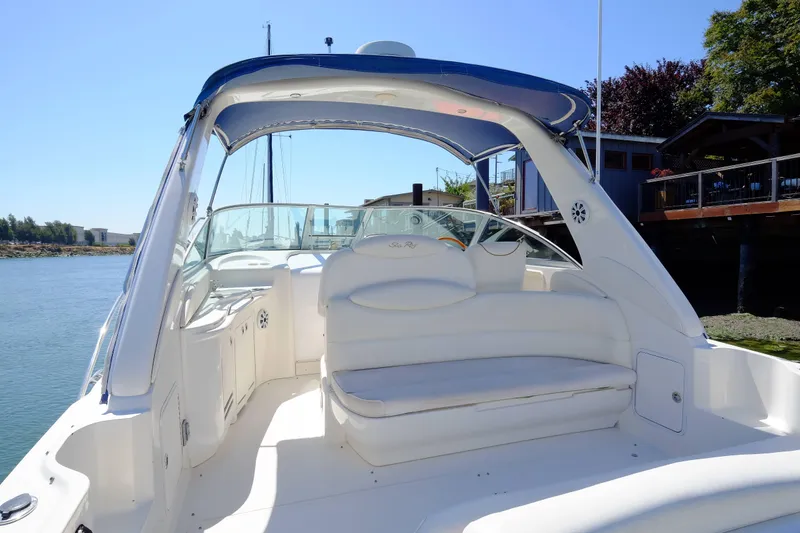 Slide: The Image of 2000 Sea Ray 340 Sundancer boat with spacious white seating and canopy, docked by the water. - 3