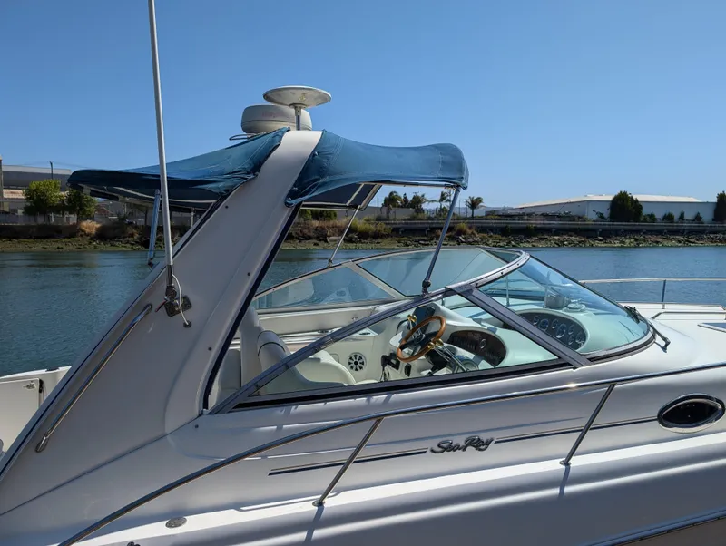 Slide: The Image of 2000 Sea Ray 340 Sundancer boat with blue canopy, docked by the water. - 34