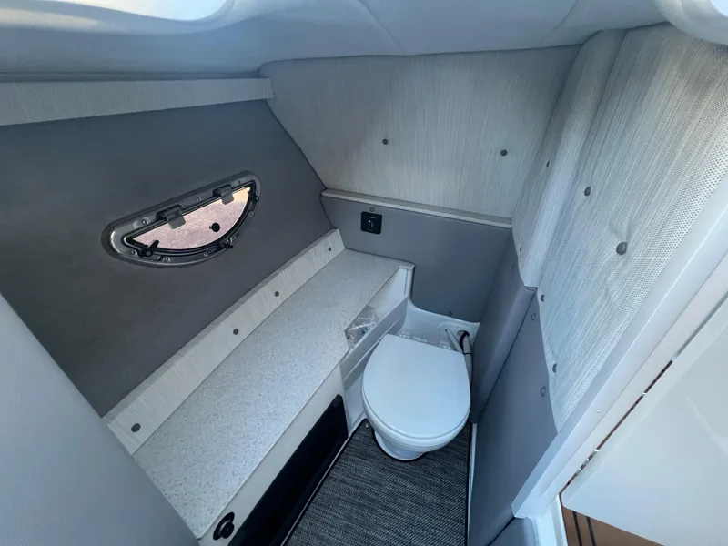 Slide: The Image of 2023 Cobalt R6 Surf boat interior with compact bathroom and porthole window. - 12