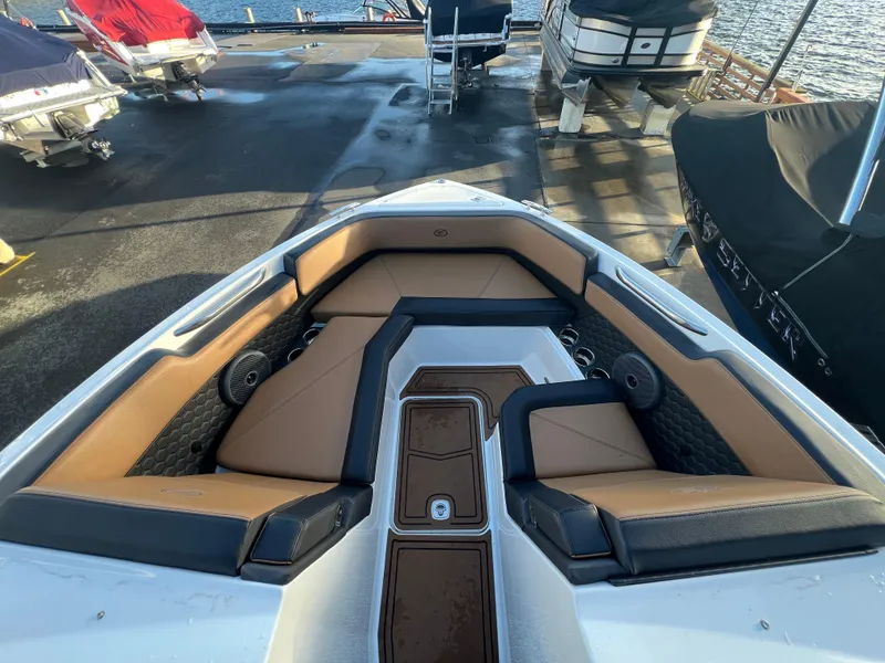 Slide: The Image of 2023 Cobalt R6 Surf boat interior with tan and black seating at a marina. - 14