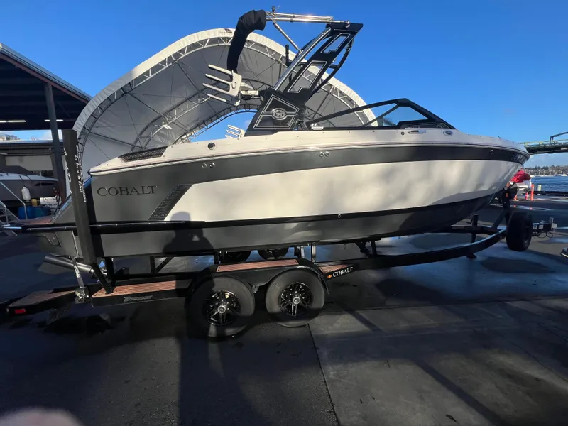 Slide: The Image of 2023 Cobalt R6 Surf boat on trailer at marina under clear blue sky. - 2