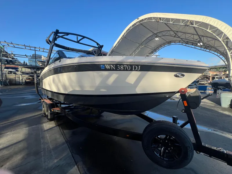 Slide: The Image of 2023 Cobalt R6 Surf boat on trailer under canopy, side view. - 3