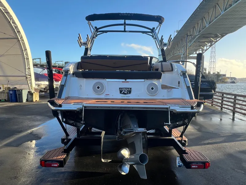 Slide: The Image of 2023 Cobalt R6 Surf boat docked under a bridge, rear view. - 6
