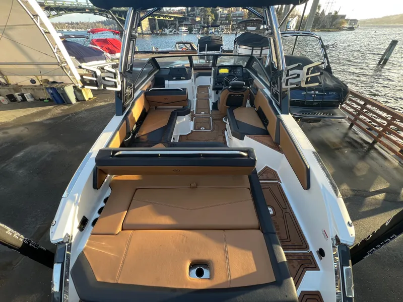 Slide: The Image of 2023 Cobalt R6 Surf boat interior with tan seating and modern dashboard at a marina. - 7