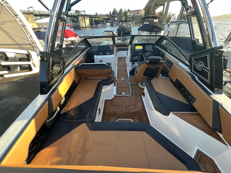 Slide: The Image of 2023 Cobalt R6 Surf boat interior with tan seating and modern dashboard, docked by the water. - 8