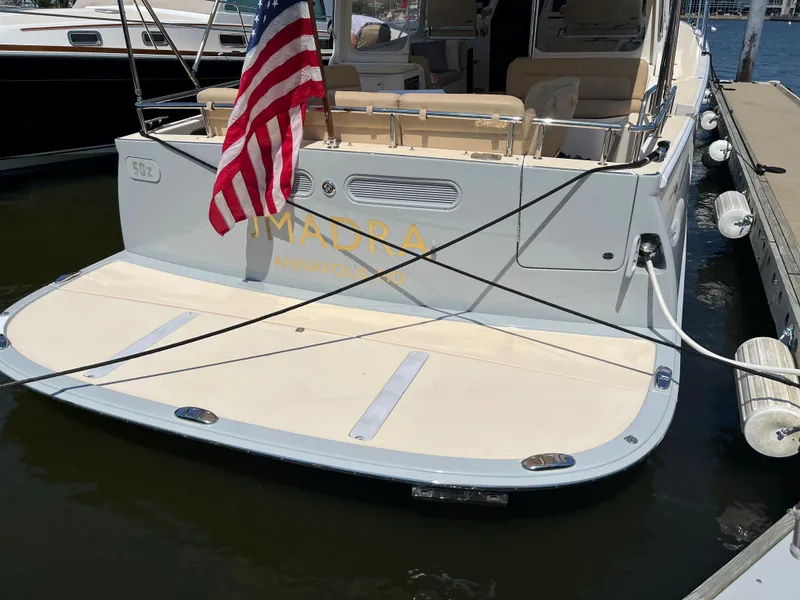 Slide: The Image of Stern view of a 2016 MJM 50z yacht docked, featuring an American flag. - 3