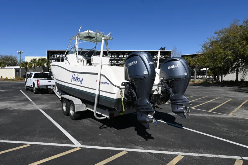 Slide: The Image of 1998 World Cat 266 SC boat on trailer with dual Yamaha engines in parking lot. - 3