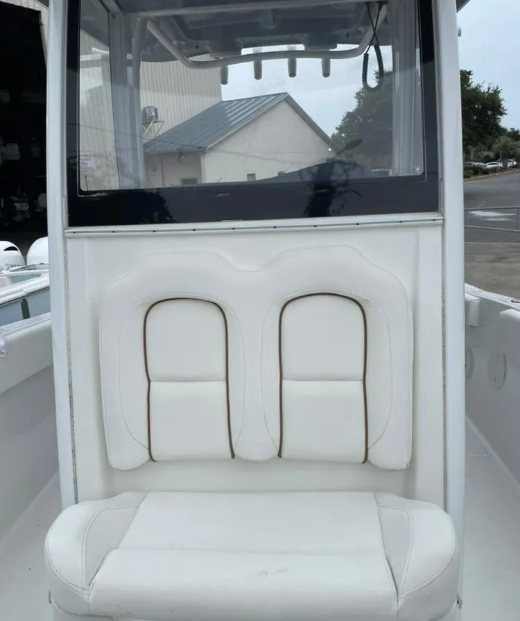 Slide: The Image of 2018 Sea Hunt Gamefish 25 boat with white cushioned seating and enclosed helm. - 12