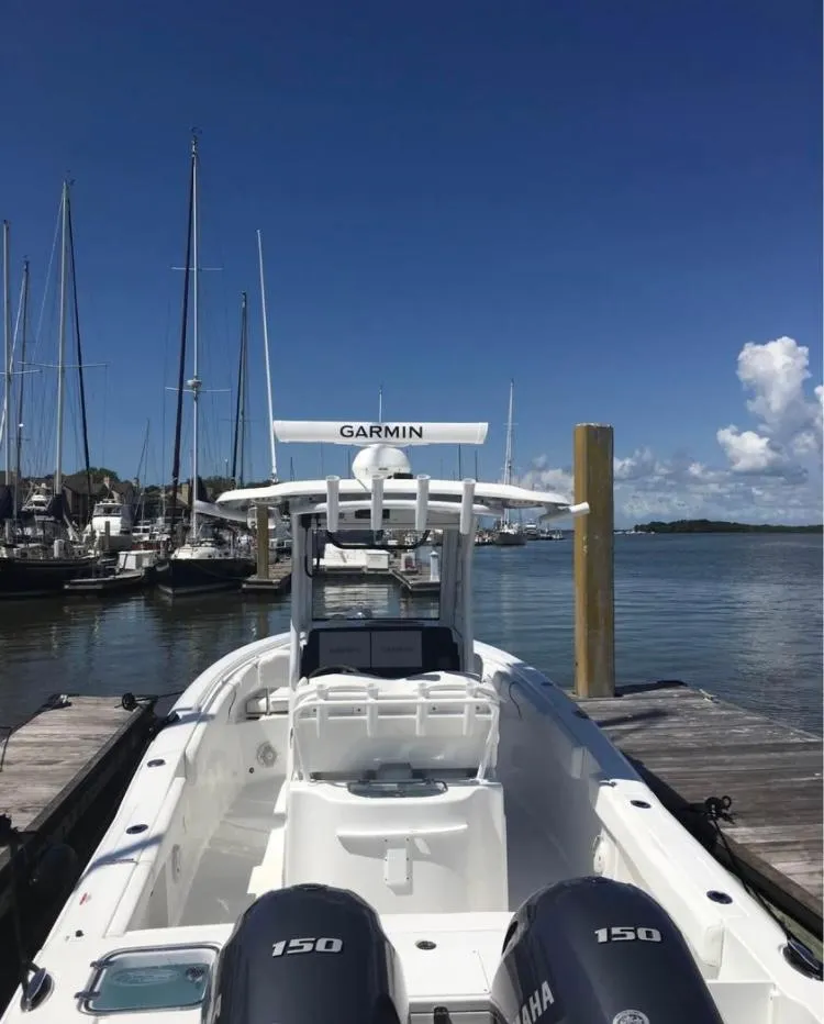 Slide: The Image of 2018 Sea Hunt Gamefish 25 boat docked, featuring dual Yamaha 150 engines, clear blue sky. - 15