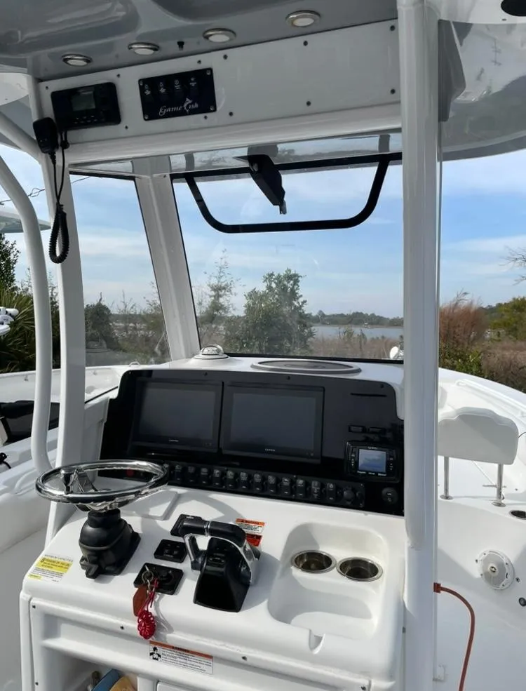 Slide: The Image of 2018 Sea Hunt Gamefish 25 boat console with steering wheel and navigation screens. - 5