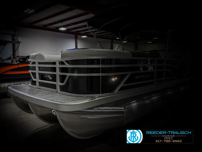 Slide: The Image of 2025 Bennington 20 SSR pontoon boat in a dimly lit showroom. - 4