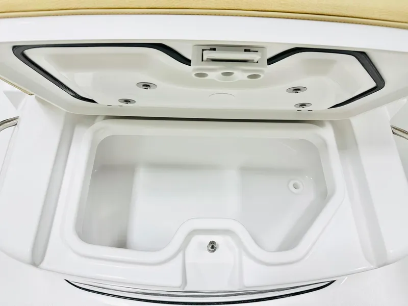 Slide: The Image of 2025 Sportsman Heritage 261 boat storage compartment, open lid, white interior, beige cushion. - 13