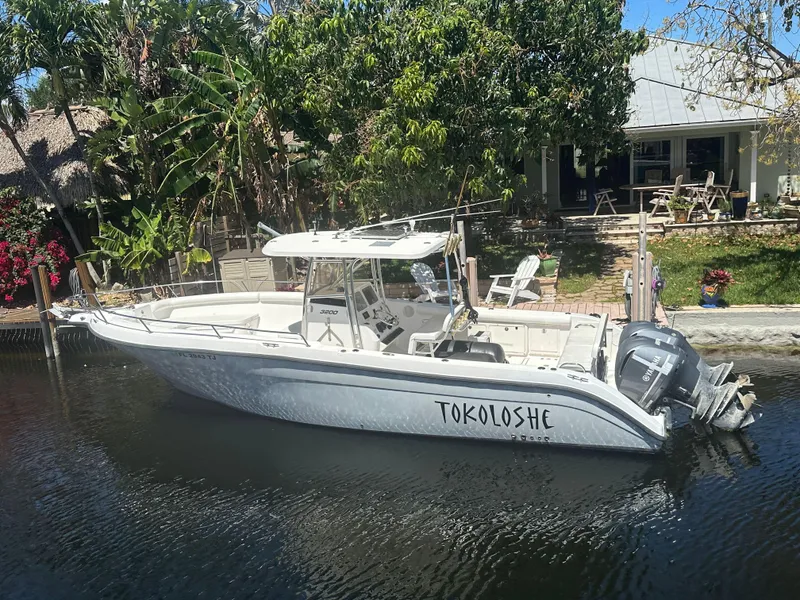 Slide: The Image of 2005 Century 3200 Center Console boat docked by a waterfront home. - 2