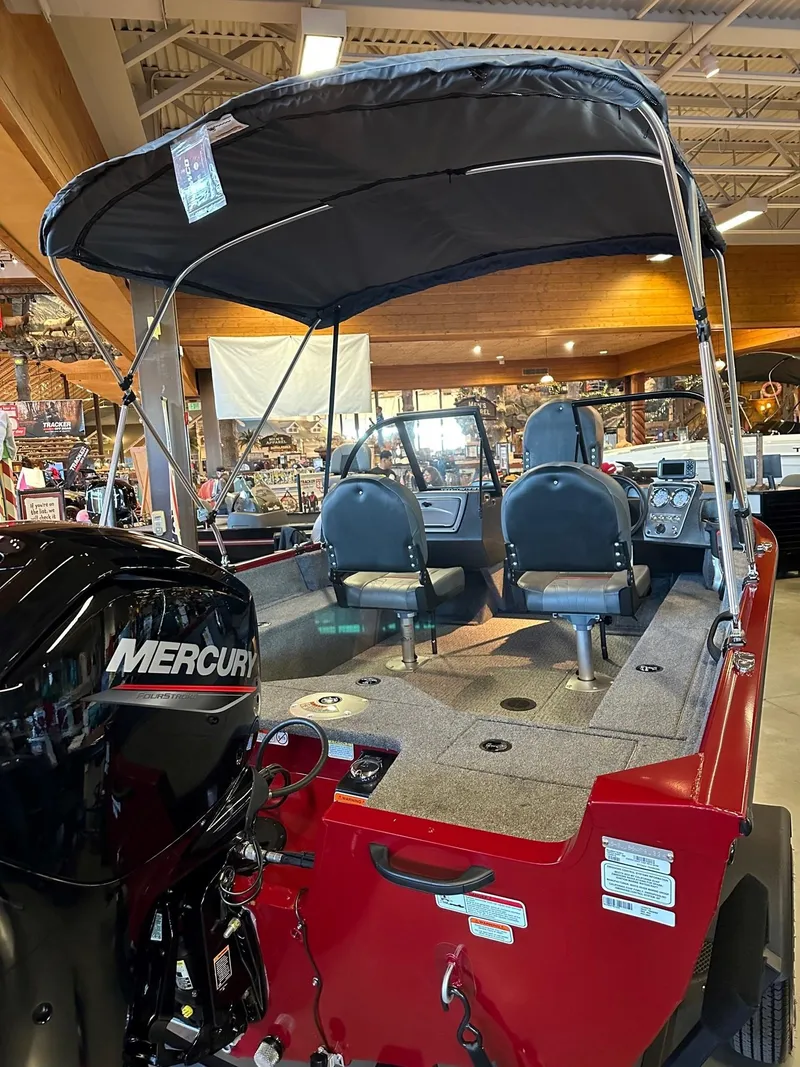 Slide: The Image of 2025 Tracker Pro Guide V-16 WT boat with Mercury engine, displayed indoors. - 2