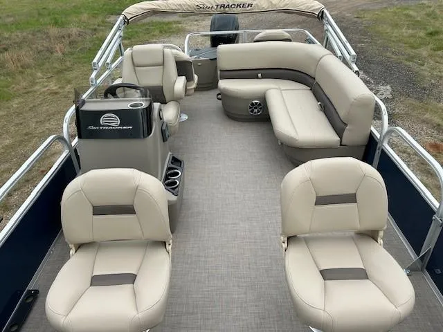 Slide: The Image of 2025 Sun Tracker Bass Buggy 18 DLX pontoon boat interior with beige seating and helm. - 10