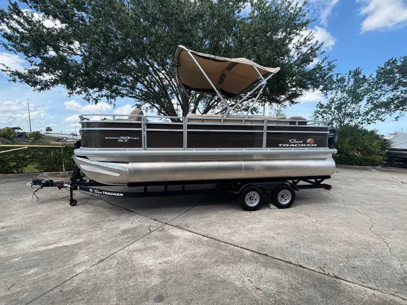 The Image of 2025 Sun Tracker SportFish 20 DLX pontoon boat on trailer, parked outdoors. - 0