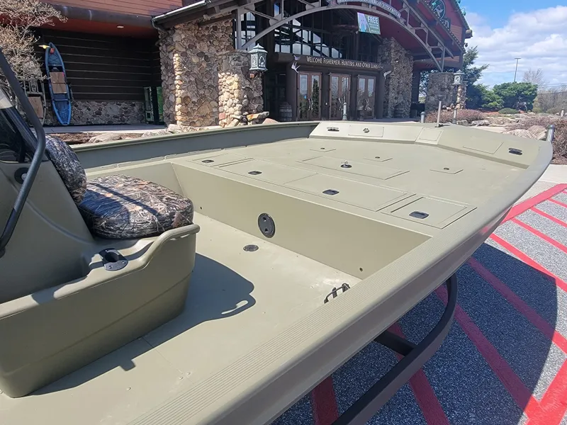 Slide: The Image of 2025 Tracker Grizzly 2072 CC boat with spacious deck, parked outside a rustic building. - 4