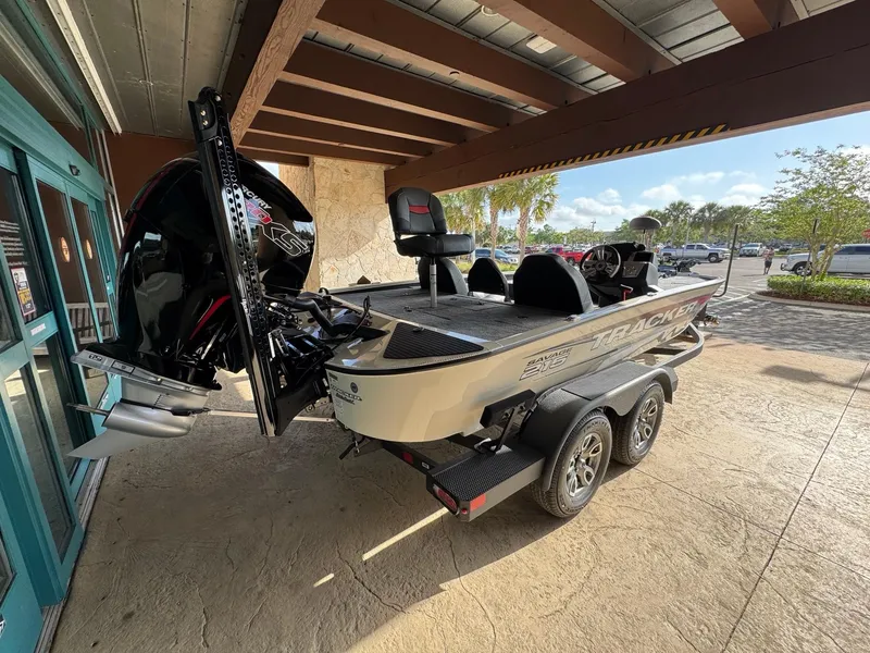 Slide: The Image of 2025 Tracker Savage 215 boat on trailer, parked under a canopy. - 2