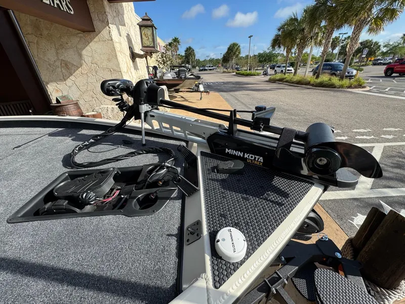 Slide: The Image of 2025 Tracker Savage 215 boat with Minn Kota trolling motor in a sunny parking lot. - 3