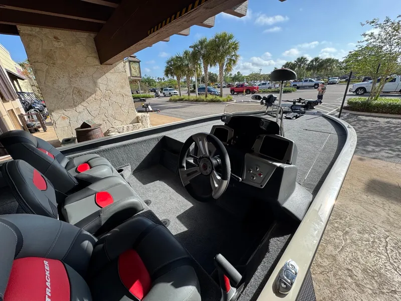 Slide: The Image of 2025 Tracker Savage 215 boat interior with steering wheel and seats in a sunny parking lot. - 5