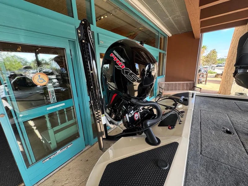 Slide: The Image of 2025 Tracker Savage 215 boat with powerful engine, parked near blue doors. - 7