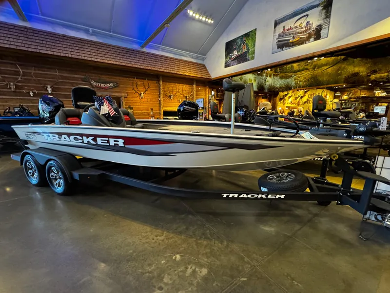The Image of 2025 Tracker Savage 215 boat displayed indoors with trailer and American flag. - 0