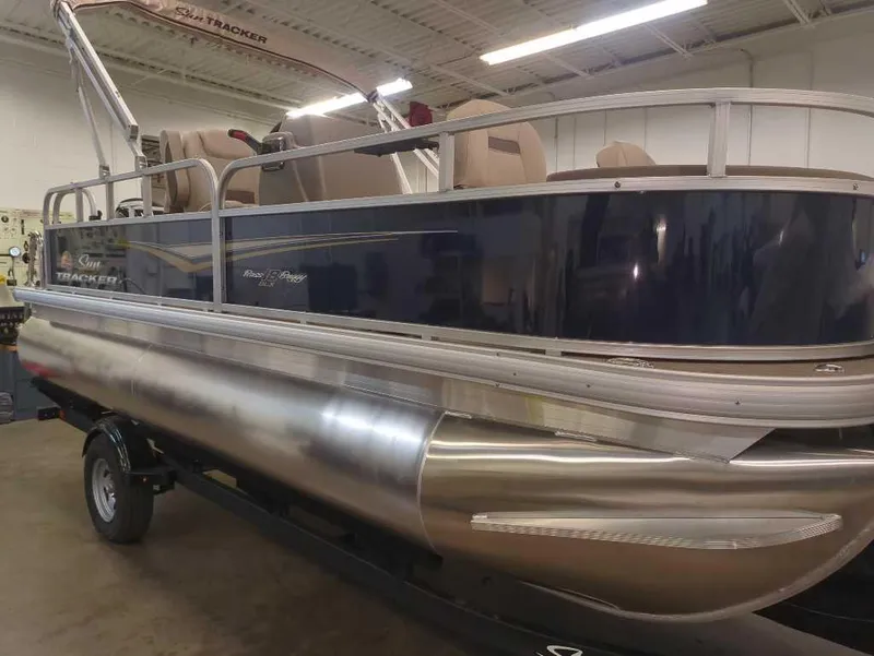 Slide: The Image of 2025 Sun Tracker Bass Buggy 18 DLX pontoon boat in showroom, side view. - 2