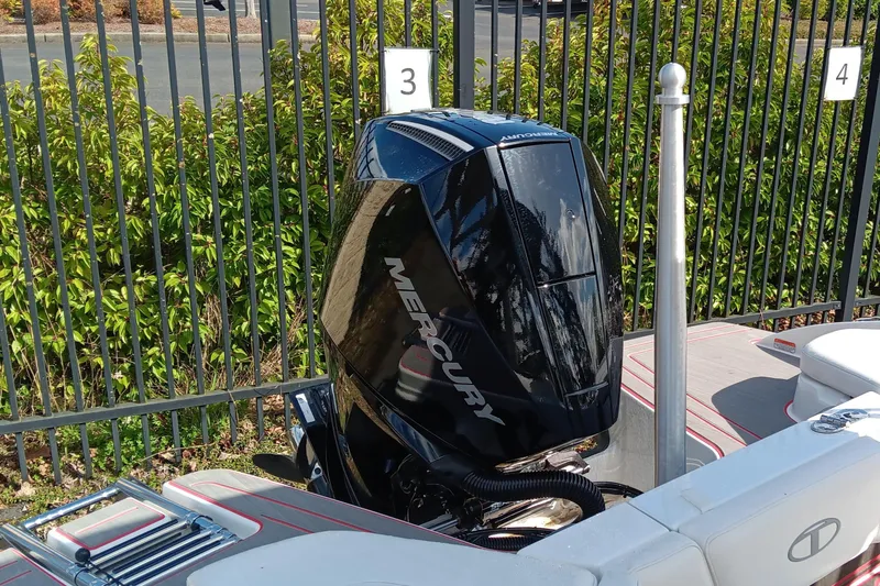 Slide: The Image of 2024 Tahoe 210 S boat with Mercury outboard motor, parked near a fence. - 7