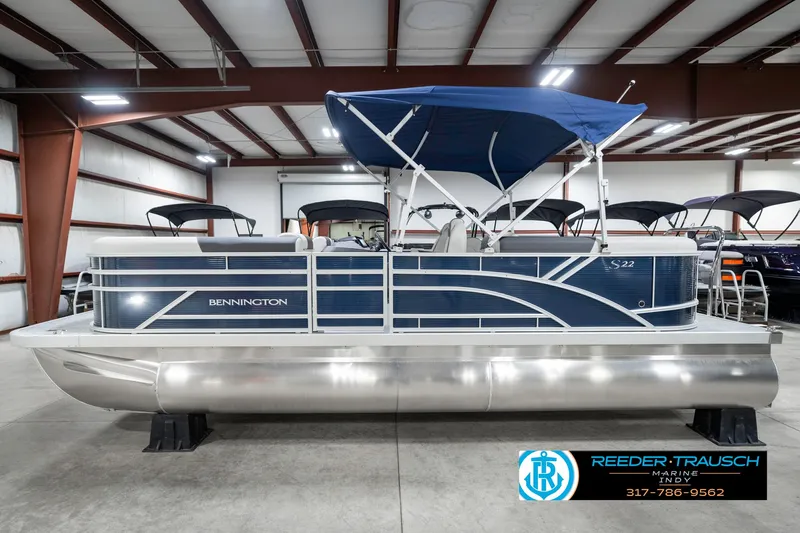 Slide: The Image of 2025 Bennington 22 SSR pontoon boat with blue canopy in a showroom. - 11