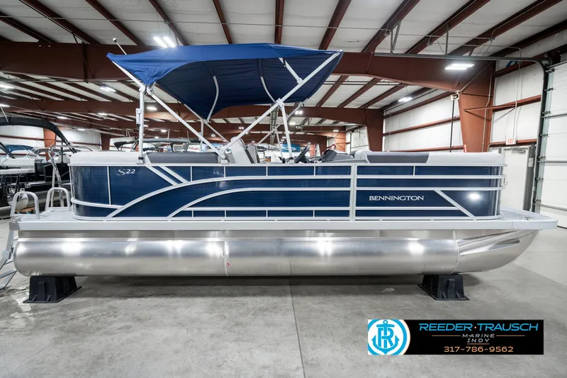 Slide: The Image of 2025 Bennington 22 SSR pontoon boat with blue canopy in indoor showroom. - 7