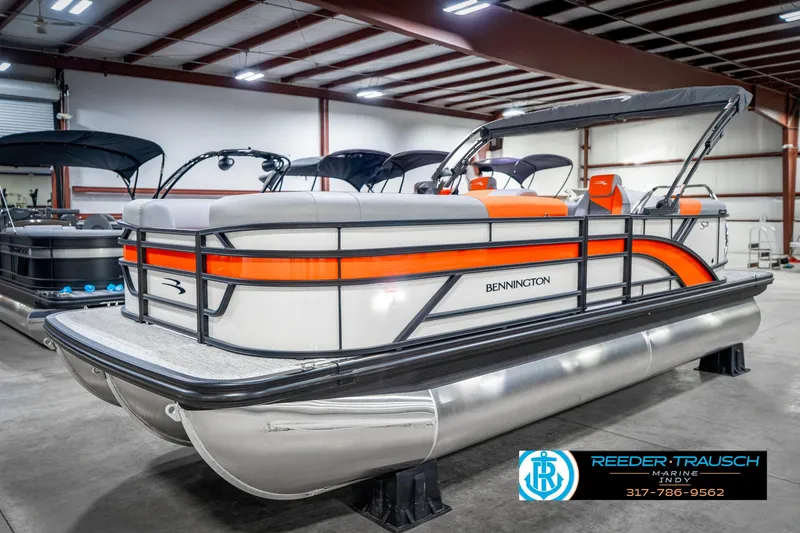 Slide: The Image of 2025 Bennington 21 SSR pontoon boat with orange accents in a showroom. - 1