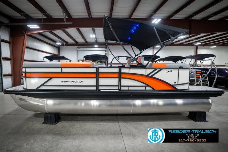 Slide: The Image of 2025 Bennington 21 SSR pontoon boat with orange accents in a showroom. - 10