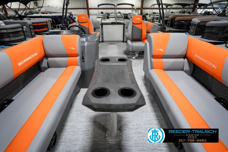 Slide: The Image of 2025 Bennington 21 SSR pontoon boat interior with orange and gray seating, cup holders, and steering console. - 15