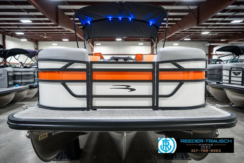 Slide: The Image of 2025 Bennington 21 SSR pontoon boat with orange accents in a showroom. - 4