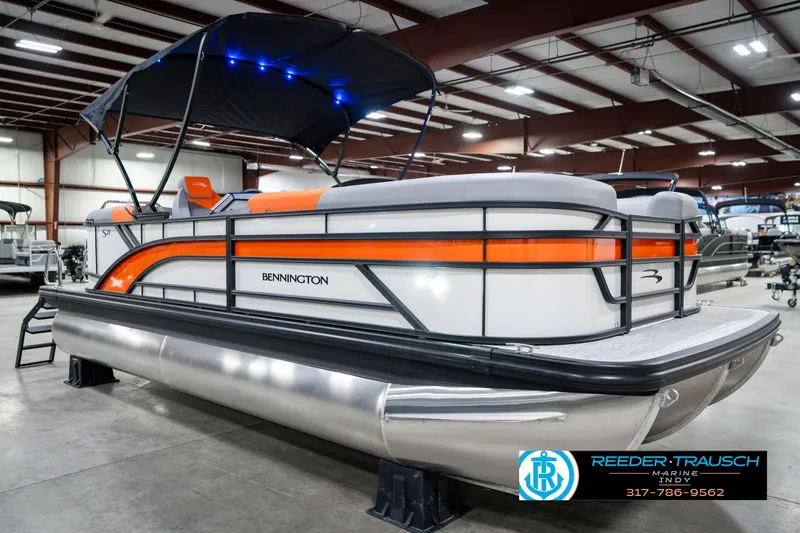 Slide: The Image of 2025 Bennington 21 SSR pontoon boat with orange accents in a showroom. - 5