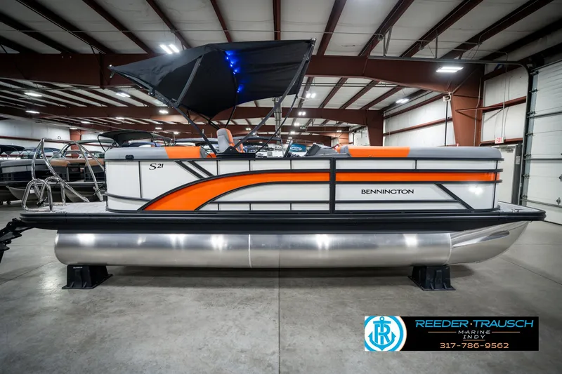 Slide: The Image of 2025 Bennington 21 SSR pontoon boat with orange accents in a showroom. - 6