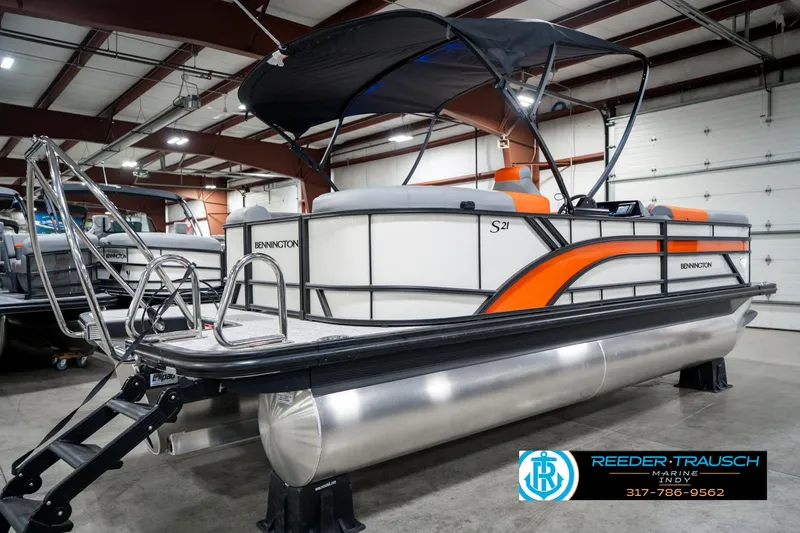 Slide: The Image of 2025 Bennington 21 SSR pontoon boat with orange accents in a showroom. - 7