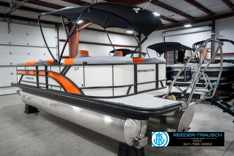 Slide: The Image of 2025 Bennington 21 SSR pontoon boat with orange accents in a showroom. - 9