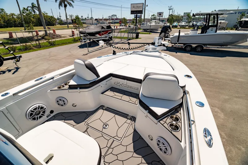 Slide: The Image of 2024 Crevalle 26 HCO boat interior with seating, speakers, and cup holders in a sunny marina. - 2